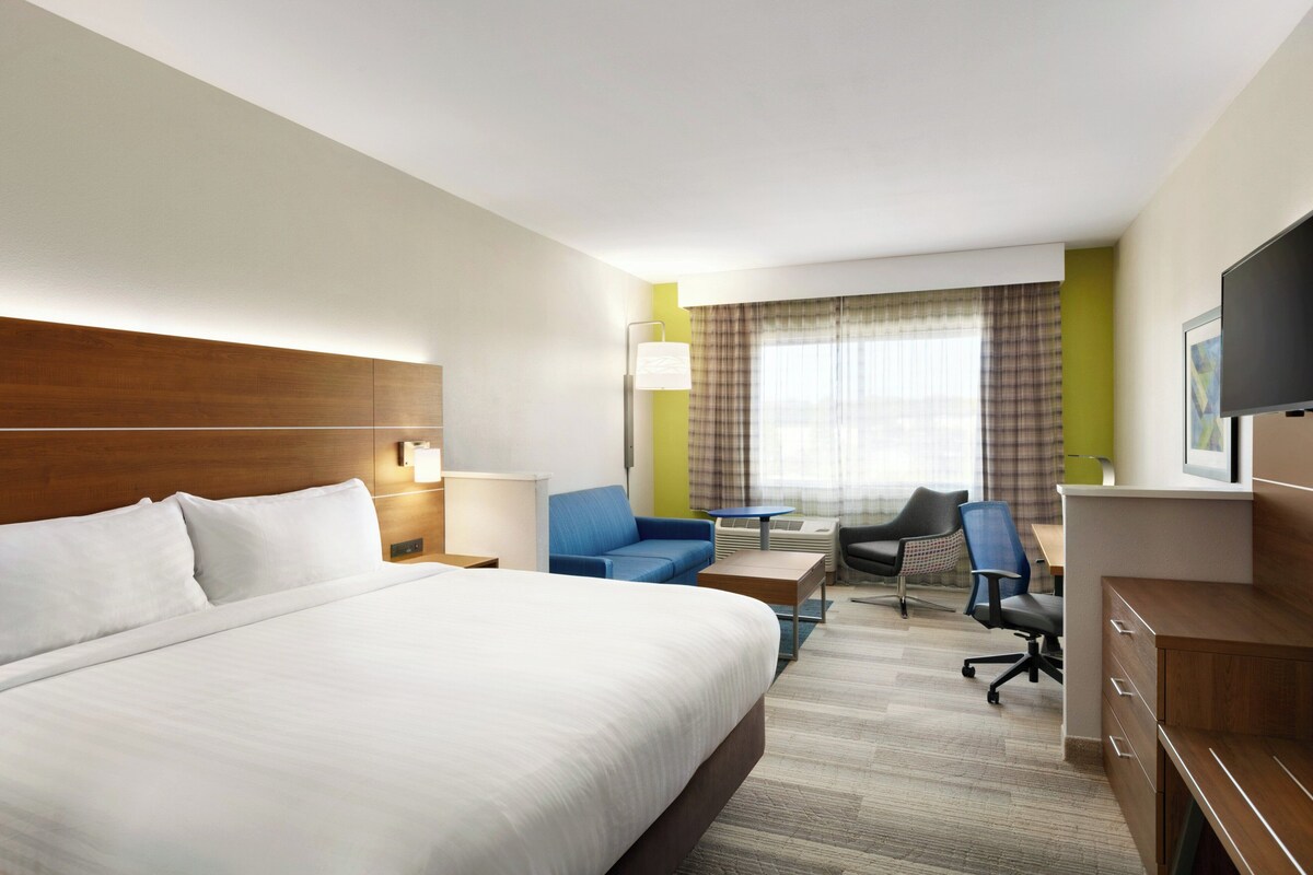 Een hotelkamer met een groot bed, een bureau, een stoel, een bank en een televisie.