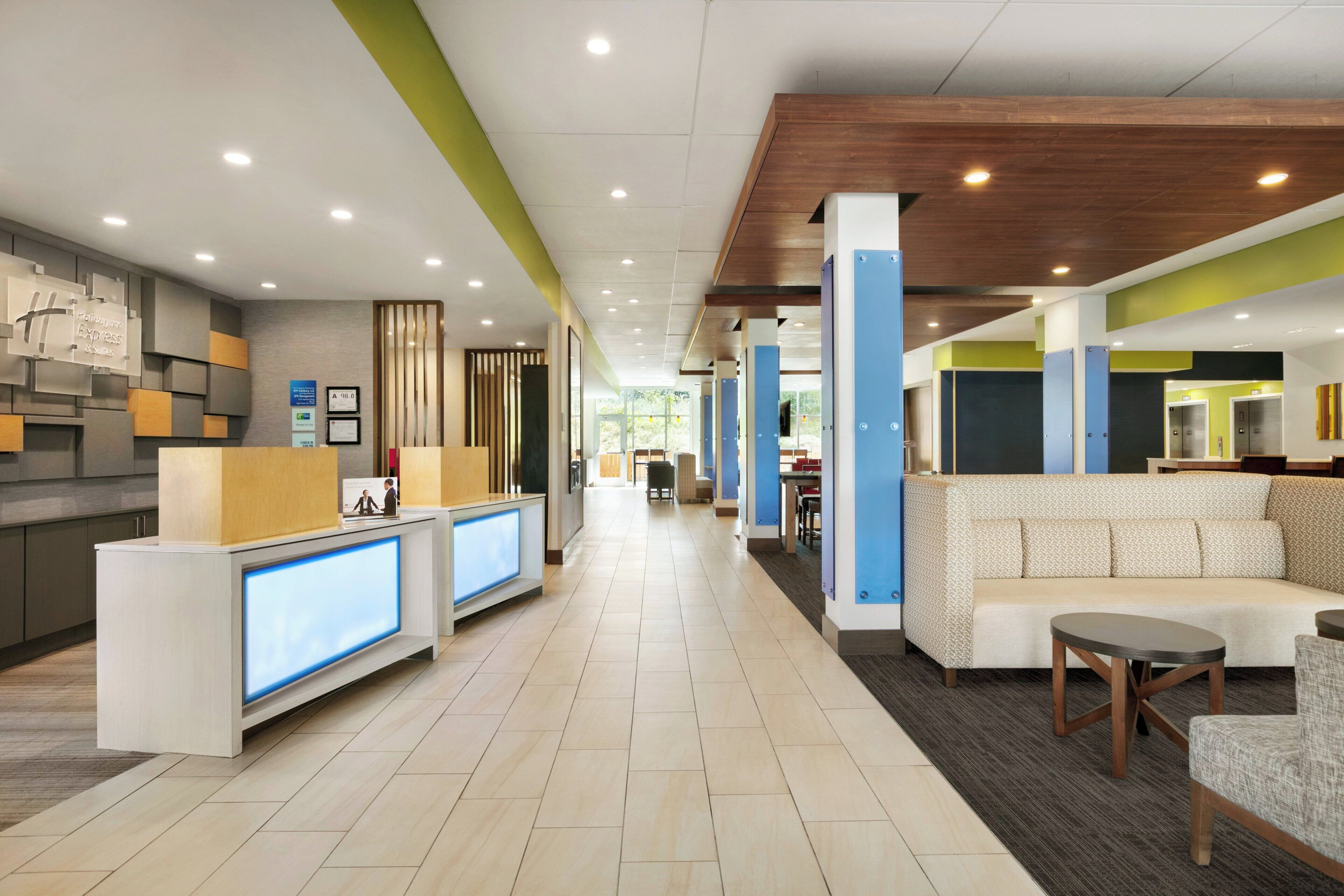 A hotel lobby with a reception desk, seating area, and a view of the hallway.