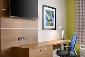 Een modern bureau met stoel, een lijst met abstract schilderij, een stopcontact en een wandlamp.