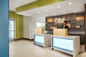 A reception area with two reception desks, a modern wall design, and a large window.