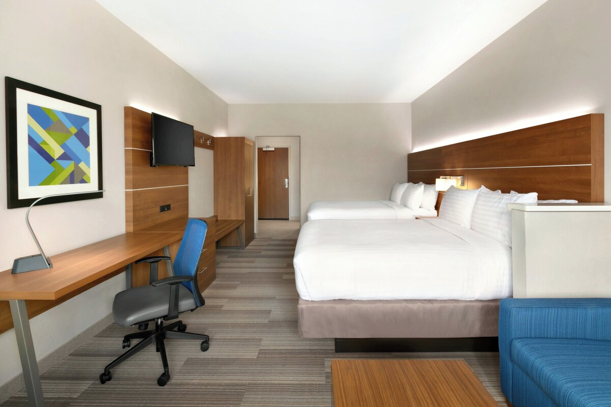 Een hotelkamer met een bed, bureau, stoel, televisie en een deur.
