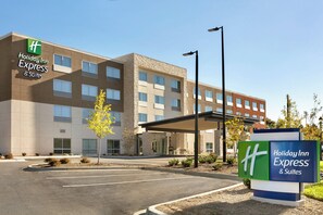 Ein Holiday Inn Express & Suites Hotel mit moderner Fassade, einem überdachten Eingangsbereich und einem Parkplatz.