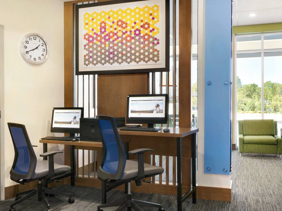 A conference room with two desks, two chairs, a clock, and a large abstract artwork on the wall.