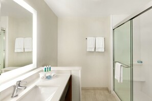 Een moderne badkamer met een grote spiegel, een wastafel en een douchecabine met glazen wanden.