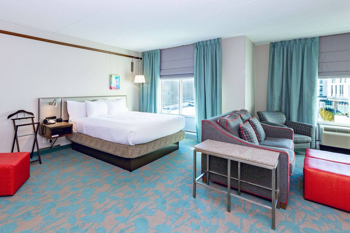 A hotel room with a large bed, a desk, a chair, and a sofa.