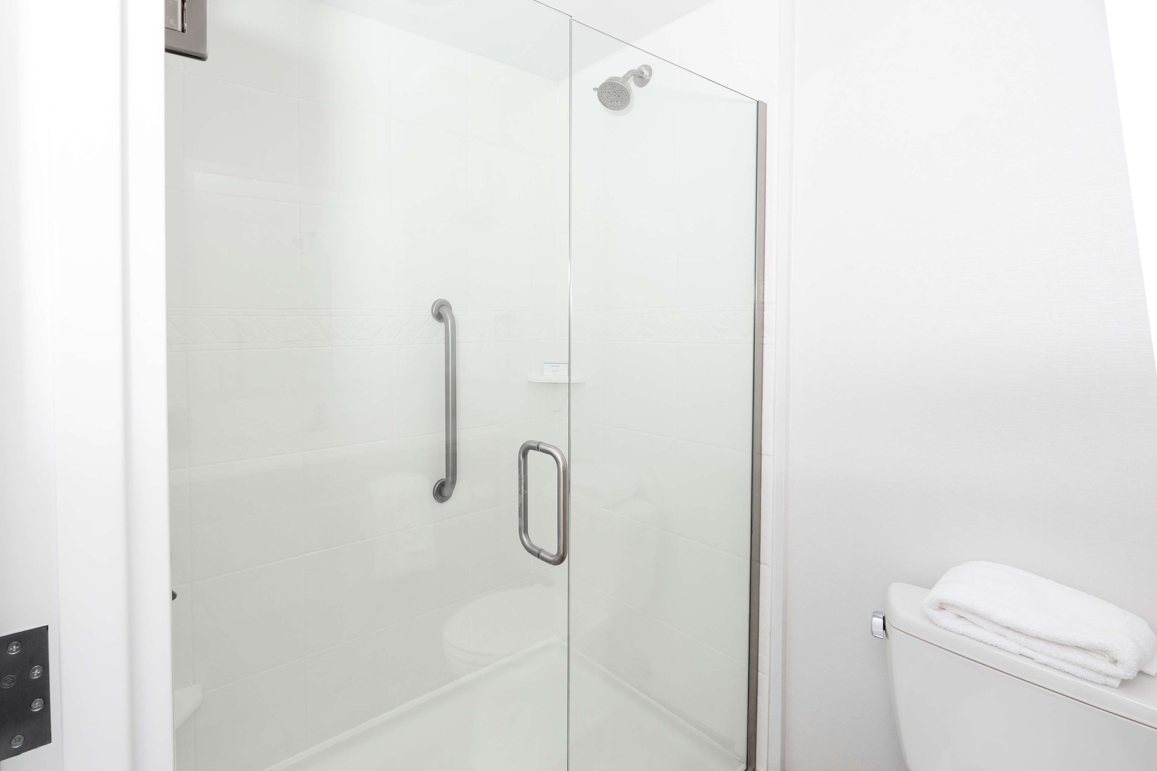 Un baño moderno con cabina de ducha de vidrio, inodoro blanco y barra para toallas.