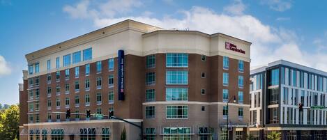 A modern hotel with multiple floors, large windows, and a prominent Hilton Garden Inn sign.