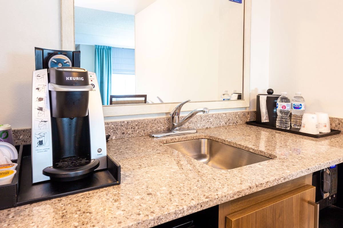 A kitchenette with a Keurig coffee maker, a sink, and a countertop.