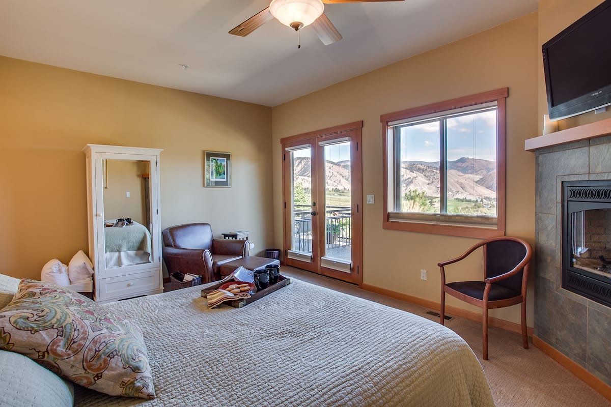 A bedroom with a bed, a chair, a desk, a wardrobe, and a fireplace.