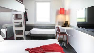 A hotel room with a bed, a desk, a chair, a TV, and a window.