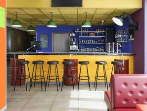 Un espace bar avec des tabourets, un comptoir et des étagères remplies de bouteilles et de verres.