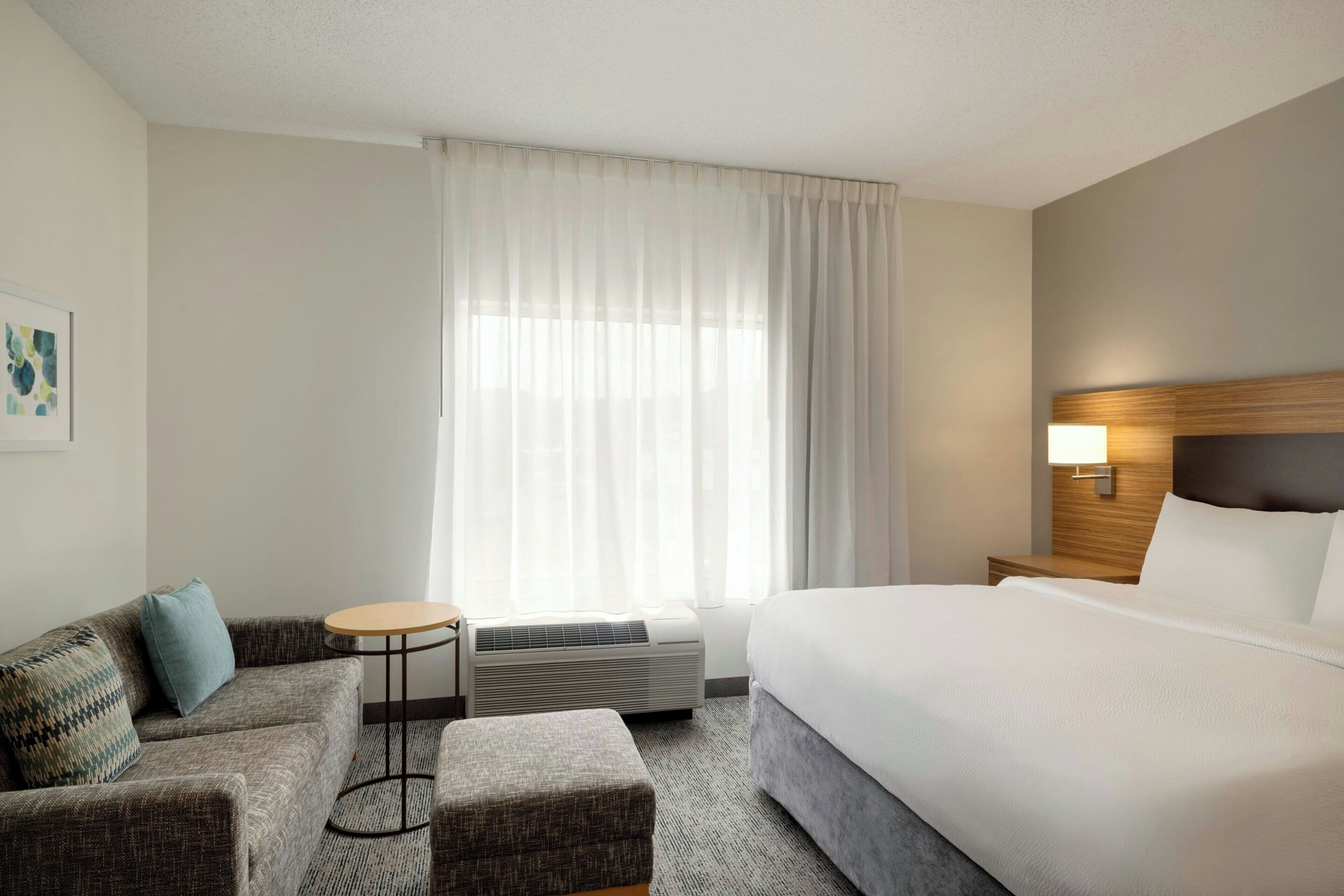 Ein Hotelzimmer mit Bett, einer Couch, einem kleinen runden Tisch und einer Wandlampe.