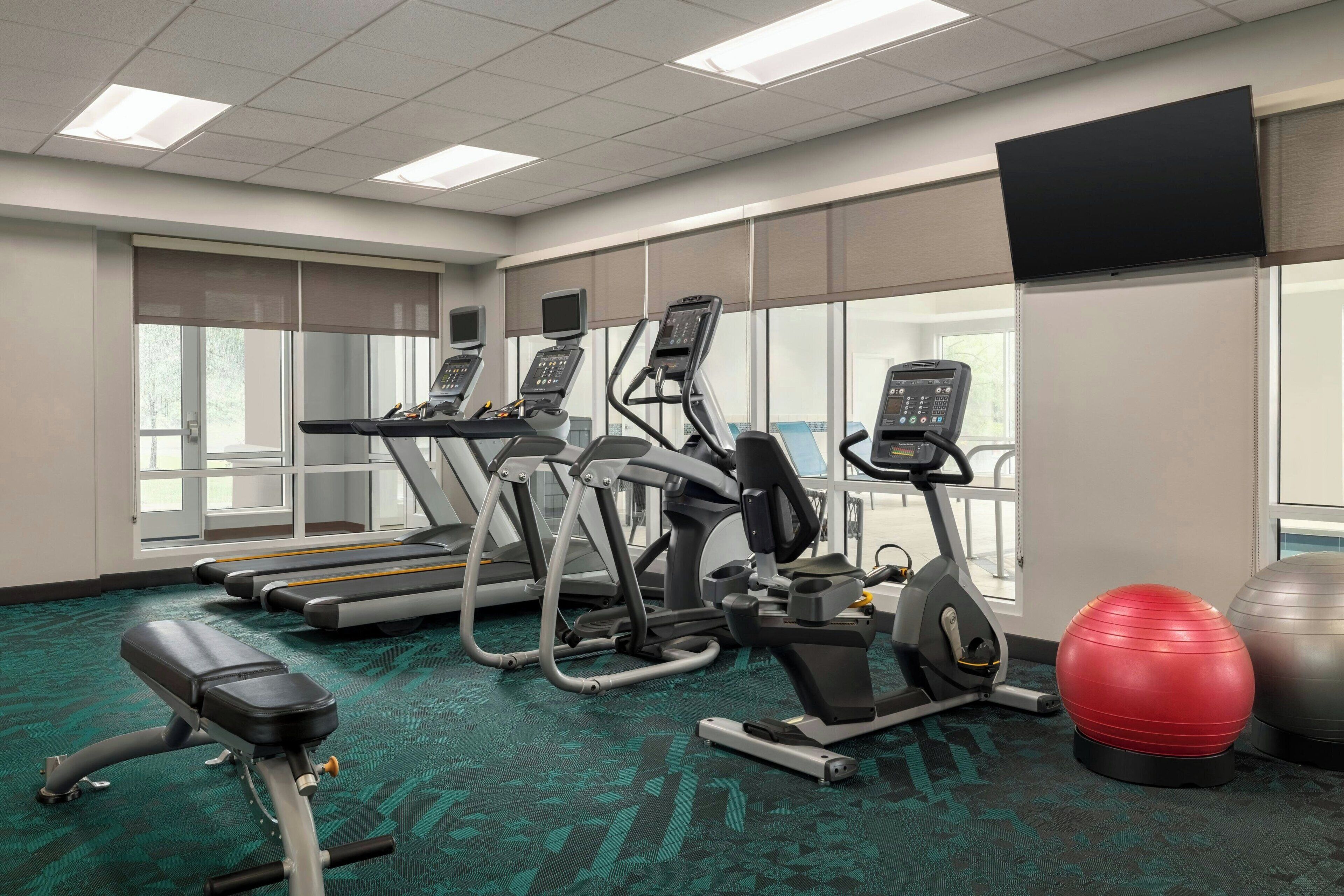 A gym with treadmills, elliptical machines, a stationary bike, and exercise balls.