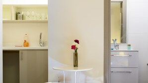 A modern bathroom with a white sink, mirror, and two stools. - Dizengoff Inn (Tel Aviv)