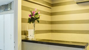 A reception area with a striped wall, a vase with flowers, and a ceiling vent. - Dizengoff Inn (Tel Aviv)