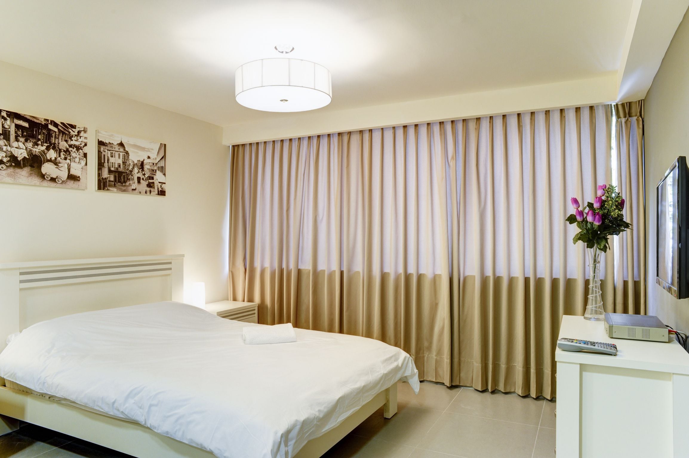 Ein Hotelzimmer mit Bett, Nachttisch, Fernseher und Fernbedienung.