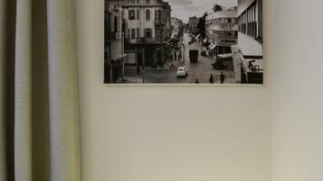 A hotel room with a bed, a nightstand with a lamp, and a wall-mounted picture of a street scene.