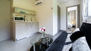 A modern kitchen with white cabinets, a microwave, and a glass-top table with a vase of flowers. - Dizengoff Inn (Tel Aviv)