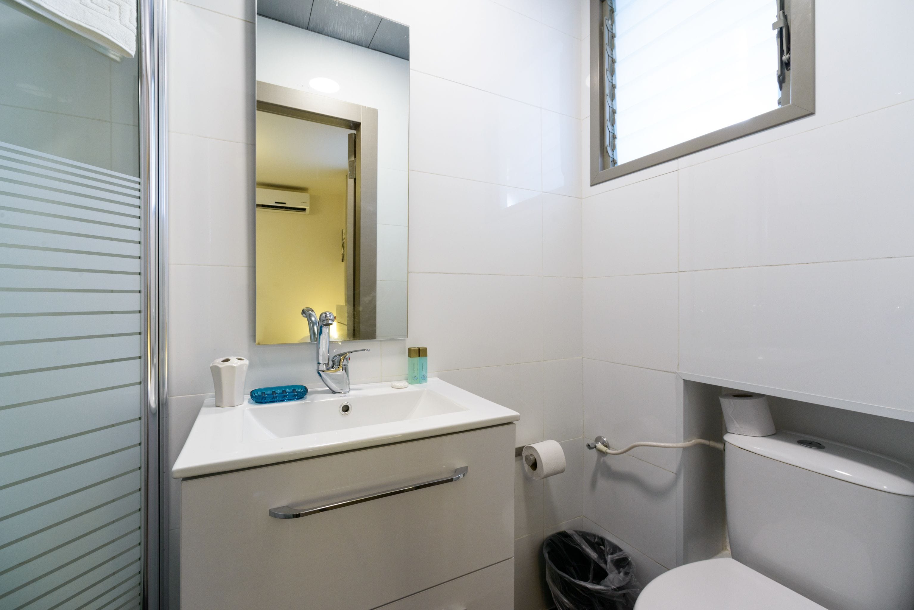 Ein modernes Badezimmer mit Waschbecken, Spiegel und Toilette in Weiß.