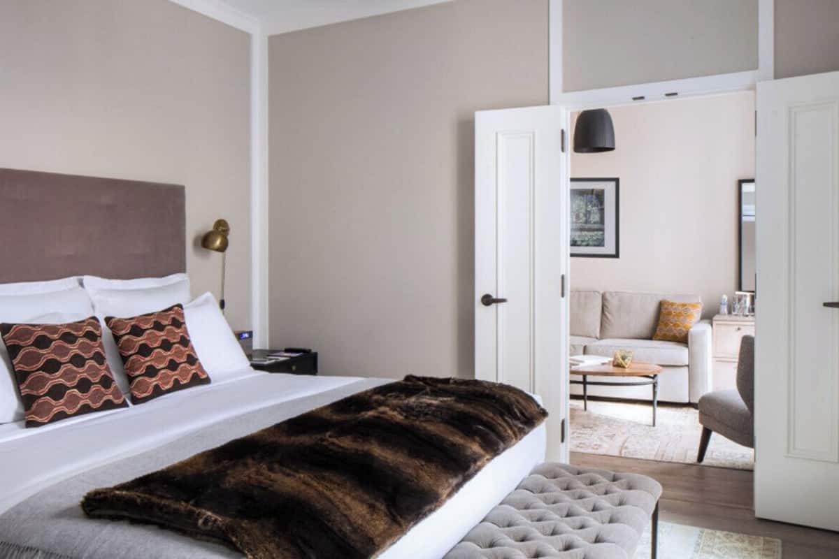A bedroom with a bed, bedside table, and a view into the living area.