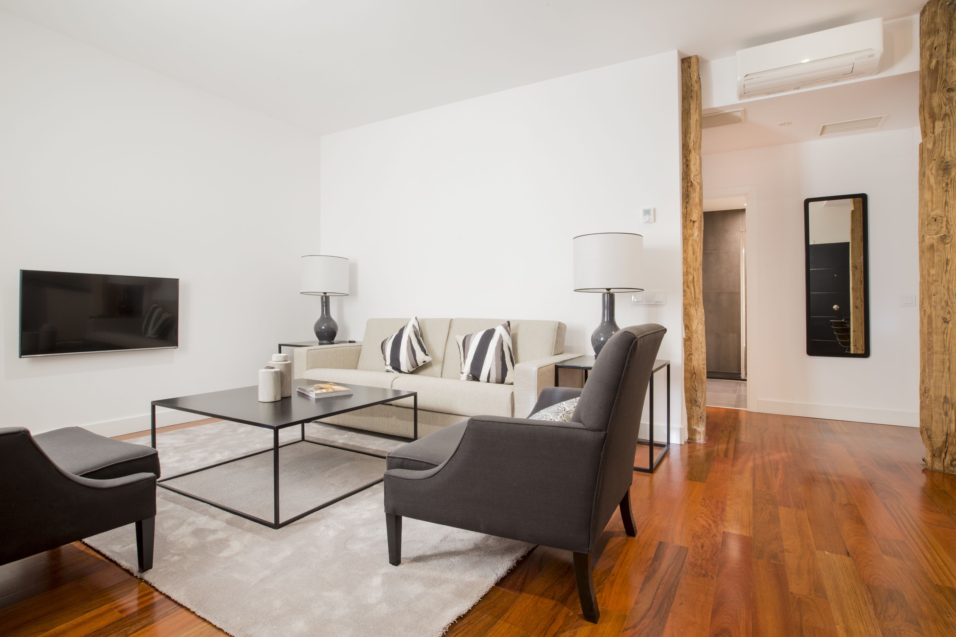 A modern living room with a sofa, two armchairs, a coffee table, and a TV.