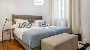A neatly arranged bedroom with a bed, bedside lamp, and a window with curtains. - Slow Suites Augusto (Madrid)