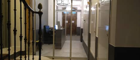 A modern interior with a staircase, a reception desk, and a glass door leading to another room.