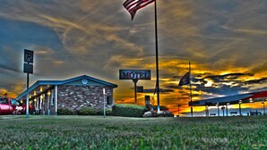 Un motel avec un panneau indiquant une vue dégagée, un drapeau américain et un coucher de soleil en arrière-plan.