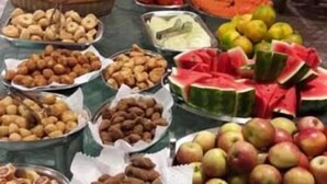 Une table de buffet proposant une variété d’aliments, notamment des fruits, des légumes et des pâtisseries.