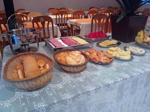 Una mesa de buffet con diferentes opciones de comida, incluyendo pan, pasteles y frutas.