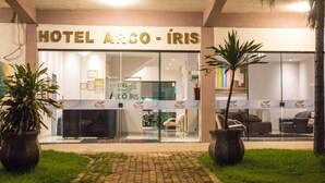 L’entrée de l’hôtel Arco-Iris, avec un comptoir d’accueil, des portes vitrées et des plantes en pot.