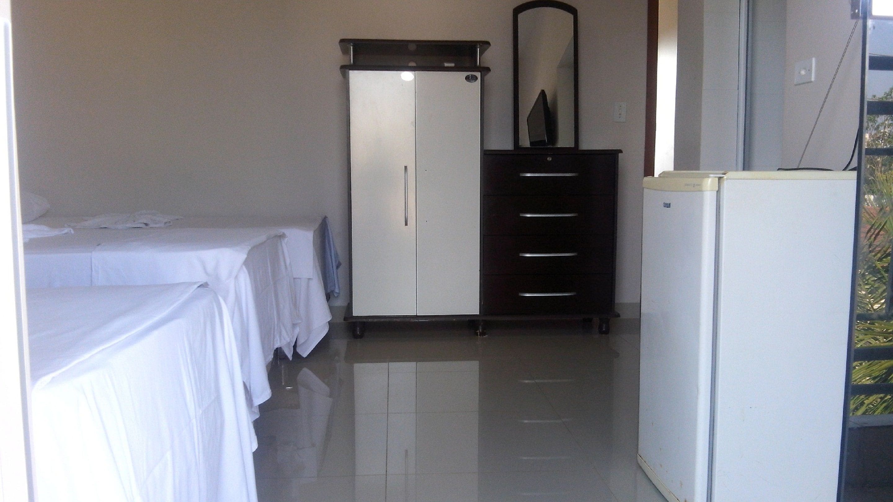 A hotel room with a bed, a wardrobe, a desk, and a refrigerator.