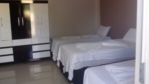Une chambre d’hôtel avec deux lits simples, une armoire et un mur uni.