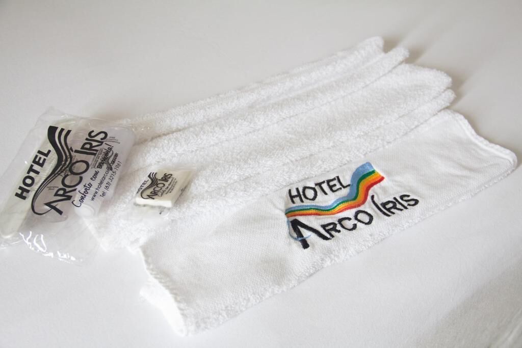 Toalha branca com o logotipo e informações de contato do Hotel Arco Iris.