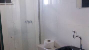 A bathroom with a glass-enclosed shower, a toilet, and a sink with a black basin.