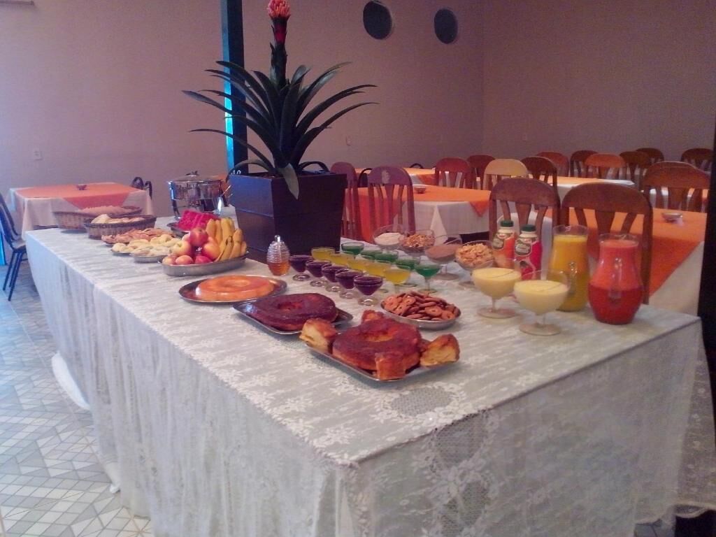 A buffet table with various food items and drinks, surrounded by chairs and tables.
