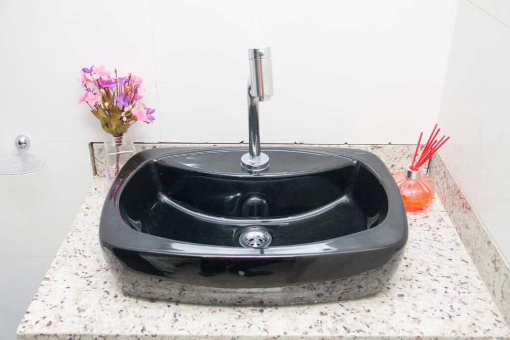 A black granite sink with a modern faucet on a speckled countertop.