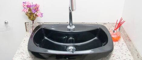 A black granite sink with a modern faucet on a speckled countertop.