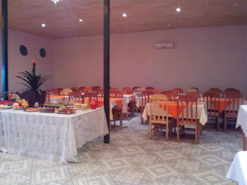A dining area with tables and chairs, a buffet table with food, and a potted plant.
