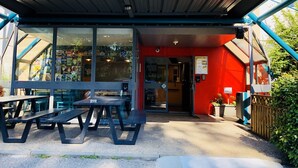 A hotel entrance with a yellow sign, outdoor seating, and a red wall. - hotelF1 Geneve Ferney Airport (Ferney-Voltaire)