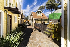 A narrow stone pathway leading to a house with a wooden deck and a green wall. - Cabañas Salamandras Avándaro  (Valle de Bravo)