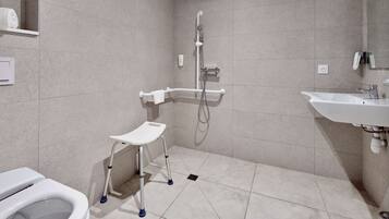 Een moderne badkamer met een toilet, een douche met handdouche, een wastafel en een klein opstapkrukje.