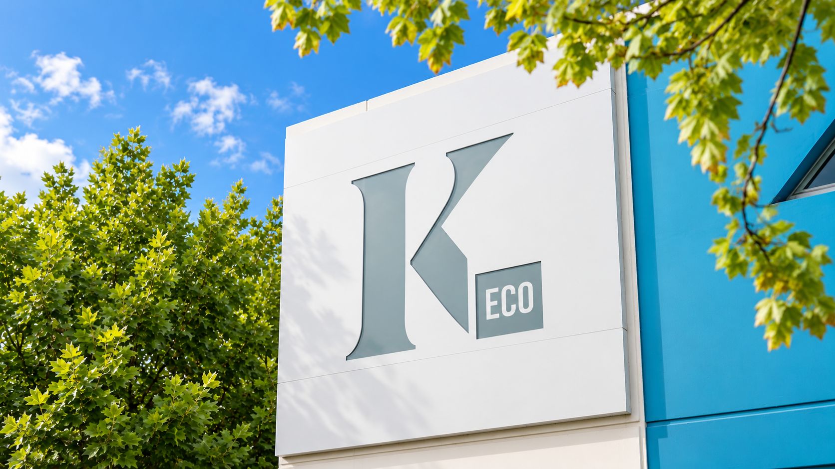A building with a large white sign featuring a stylized letter 'K' and the word 'ECO' in a smaller box.