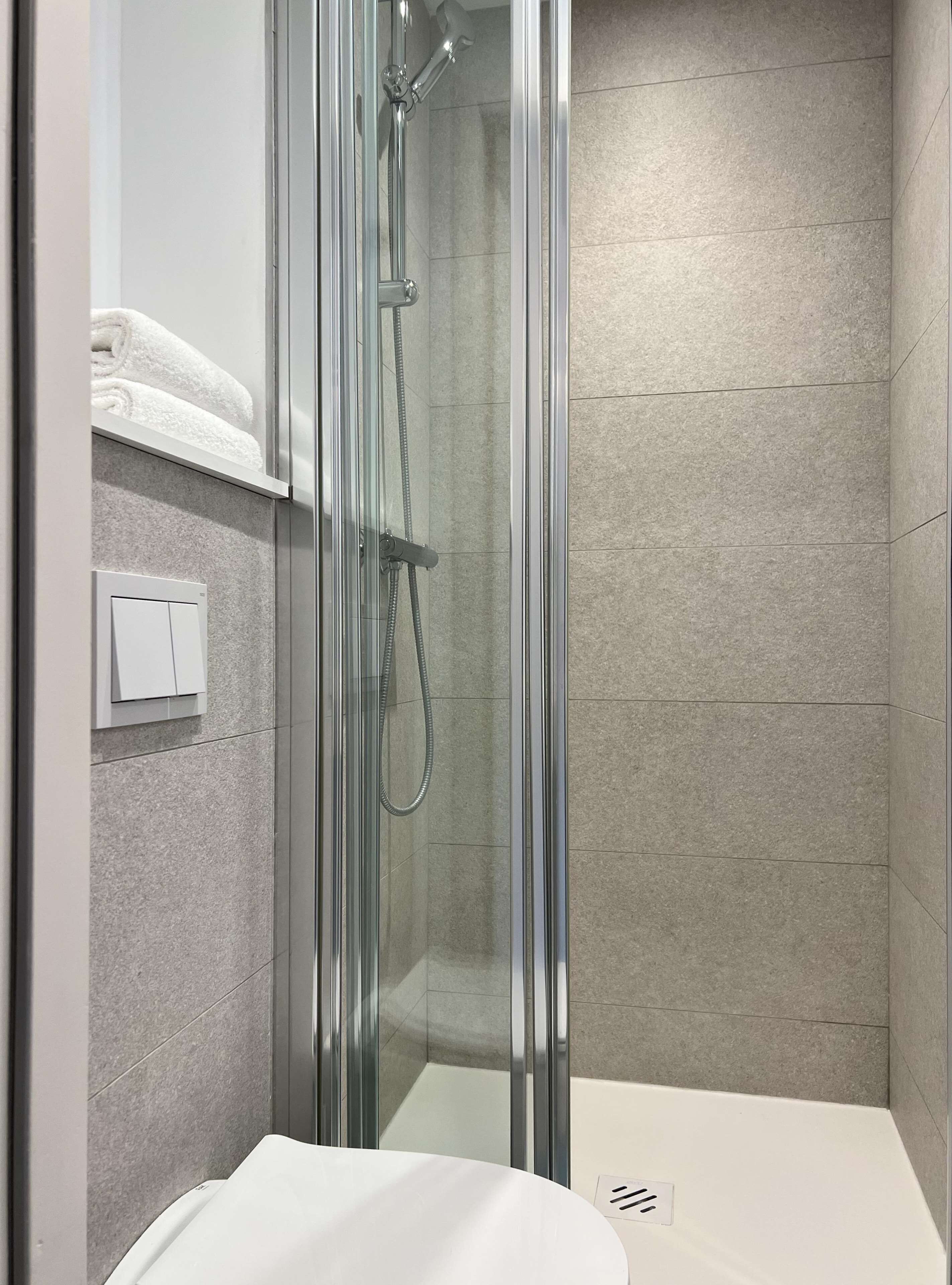 A modern bathroom with a glass-enclosed shower, a white sink, and a towel rack.