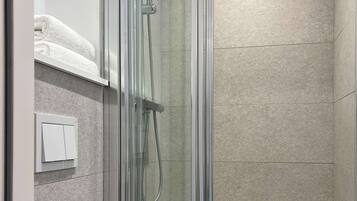 A modern bathroom with a glass-enclosed shower, a white sink, and a towel rack.