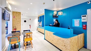 A reception area with a blue counter, wooden paneling, and a woman at the desk.