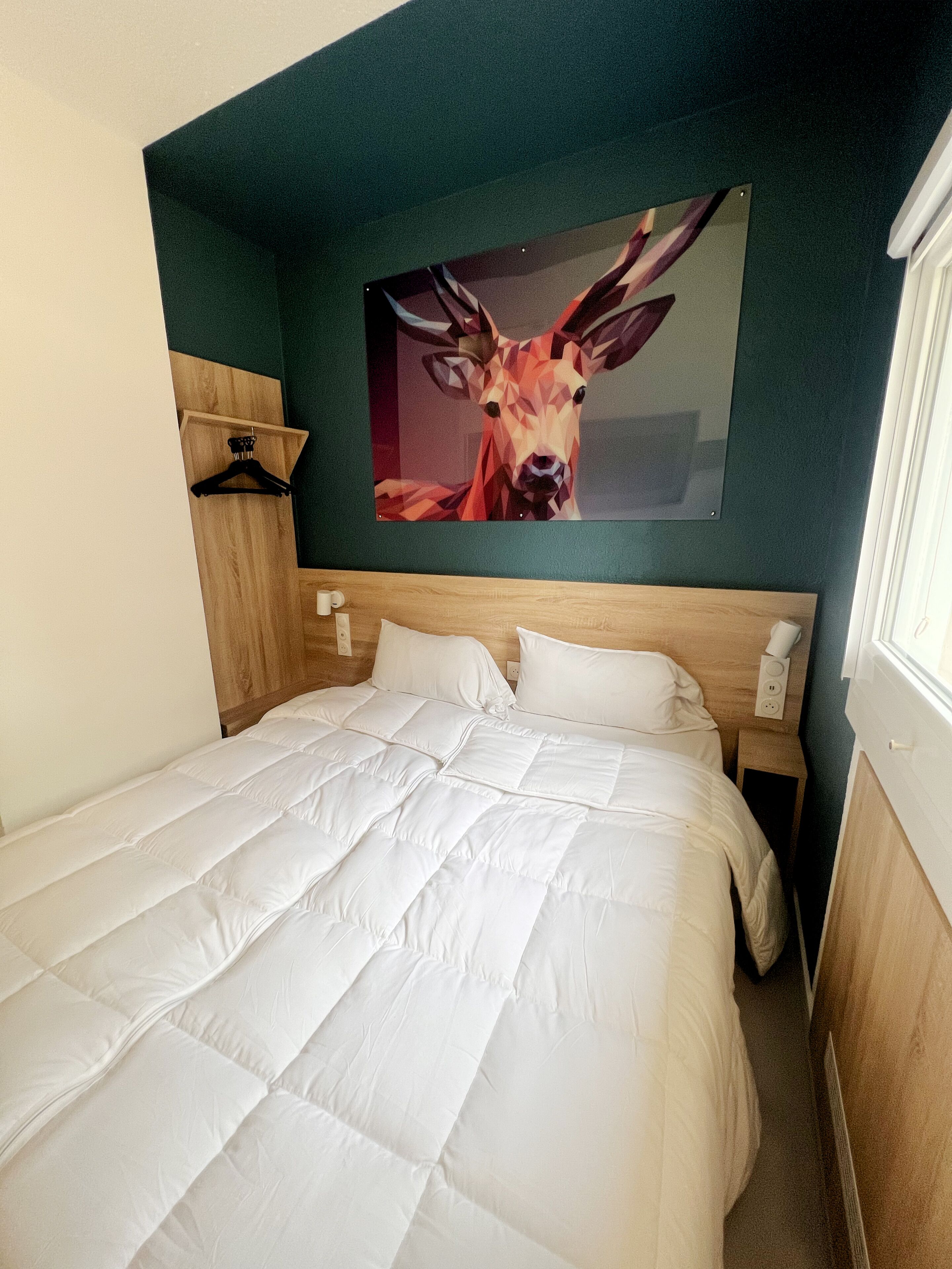 Un letto rifatto con biancheria bianca in una stanza dalle pareti color acquamarina.