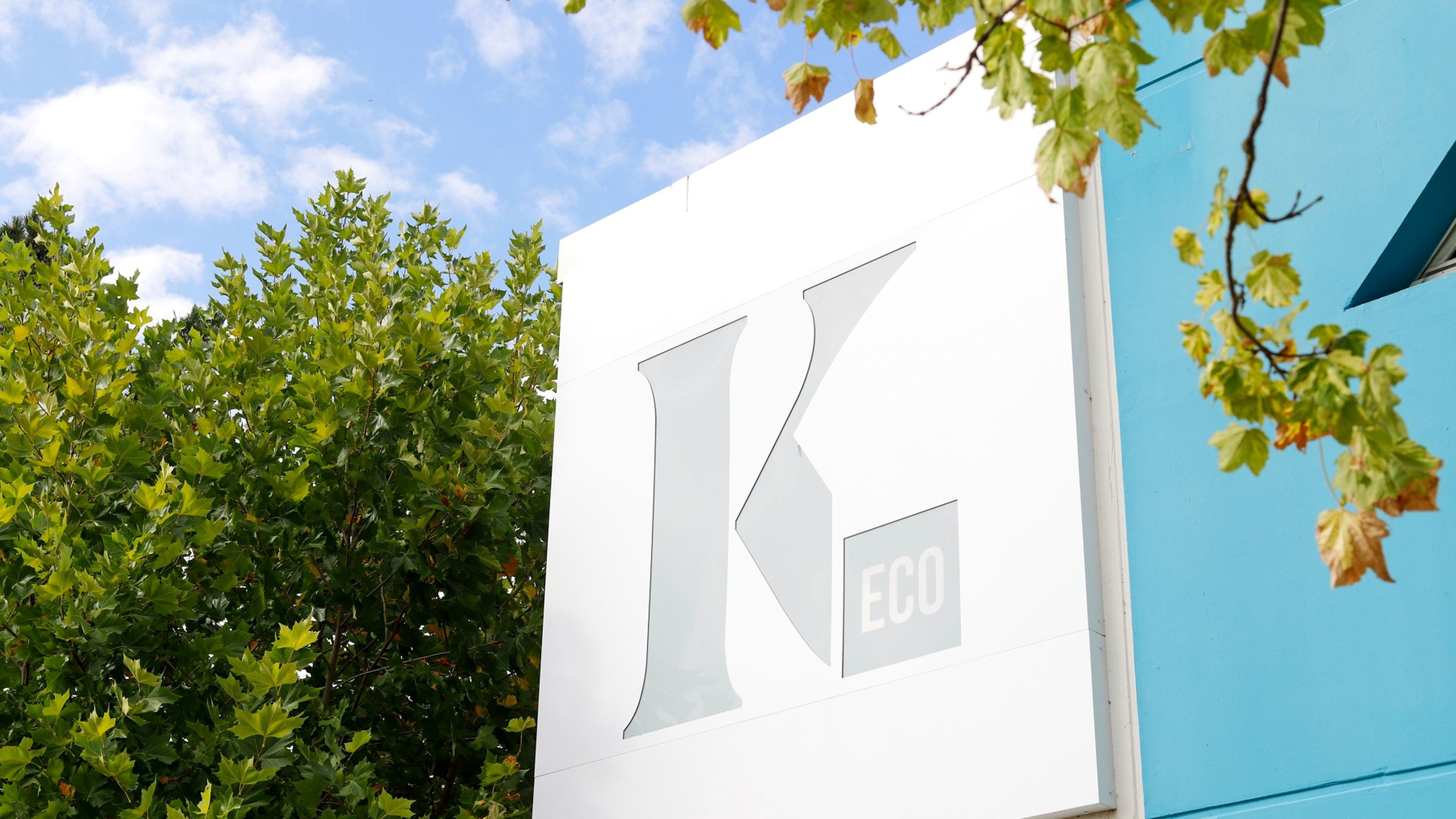 A building with a large white sign featuring a stylized letter 'K' and the text 'eco'.