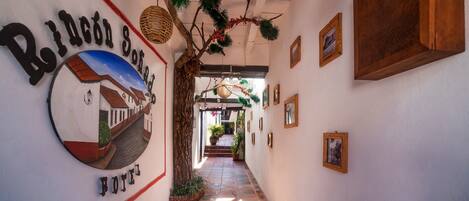 Un pasillo decorado con ramas de pino y una cesta colgante, con un letrero que indica 'Rinconado Hotel'.