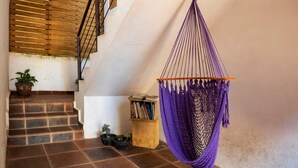 Een trap met een hangmat, planten in potten en een klein houten boekenrek.